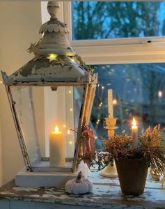 Festive Christmas candle decorations. Luxury LED pillar candle inside a rustic white lantern on a window sill